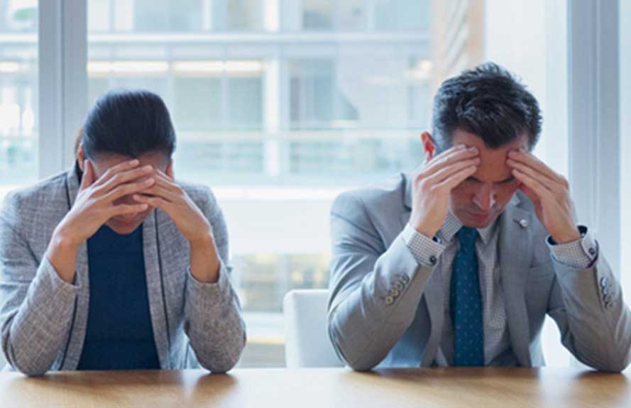 Two people holding their heads with headaches