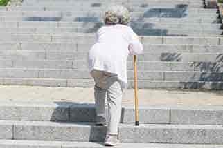 Older woman climbing stairs with a cane